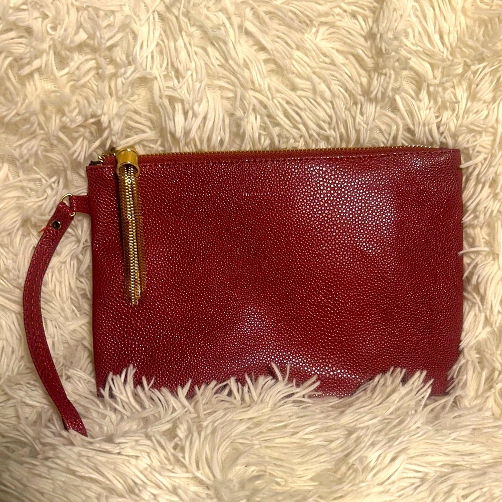 Wine red faux leather wristlet with a gold zipper.